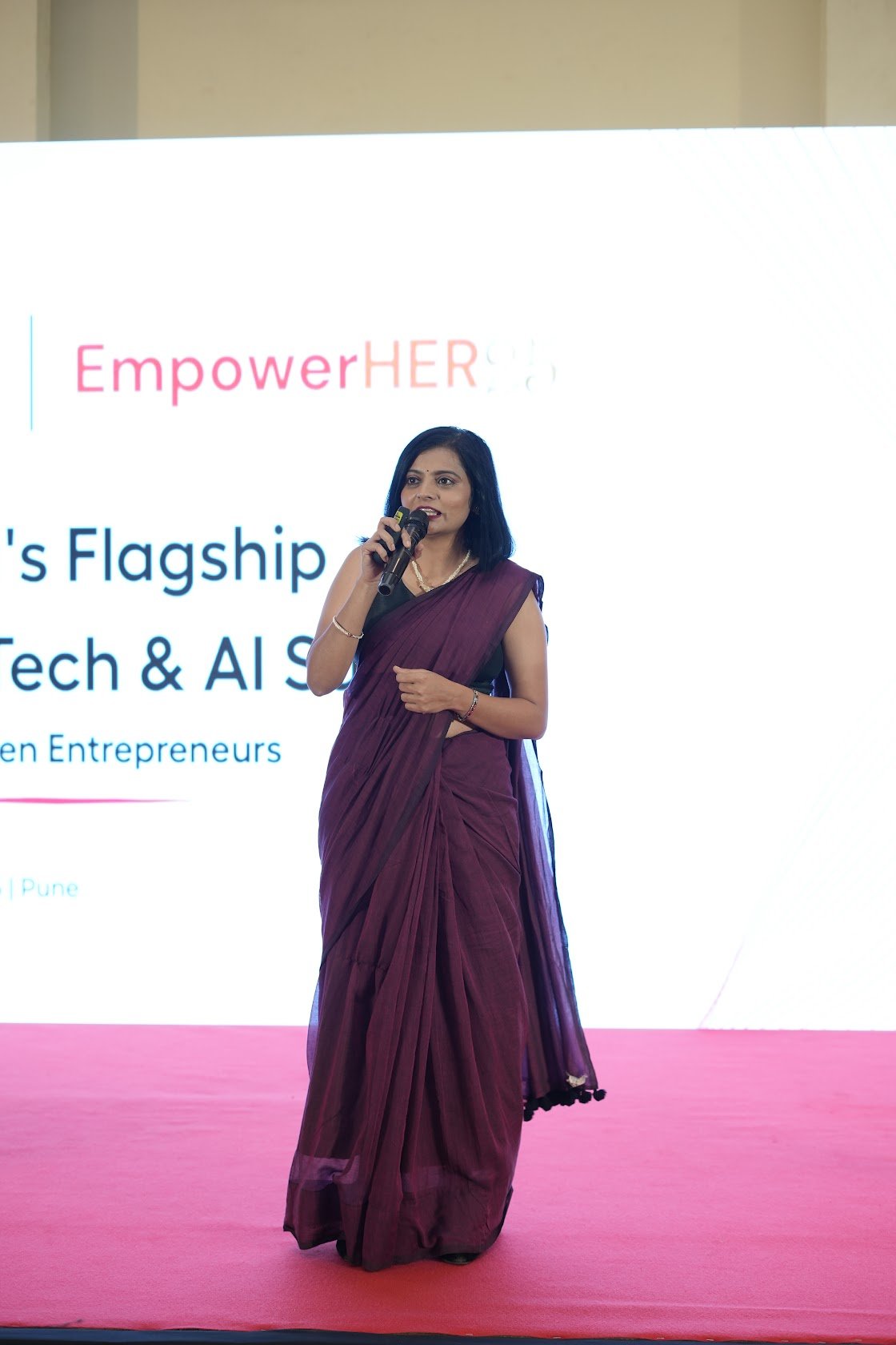 Nikita Vora speaking on stage at EmpowerHER